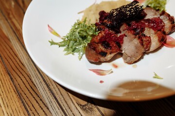 Grilled pork steak with green salad on a wooden table, top view