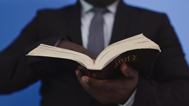 Black man turning pages of the Bible. Front View Closeup on the Book
