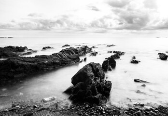 Black-and-white photograph of stones on the sea shore with a long exposure