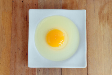 Eggs hammered on a white plate placed on a wooden table in the kitchen.top view