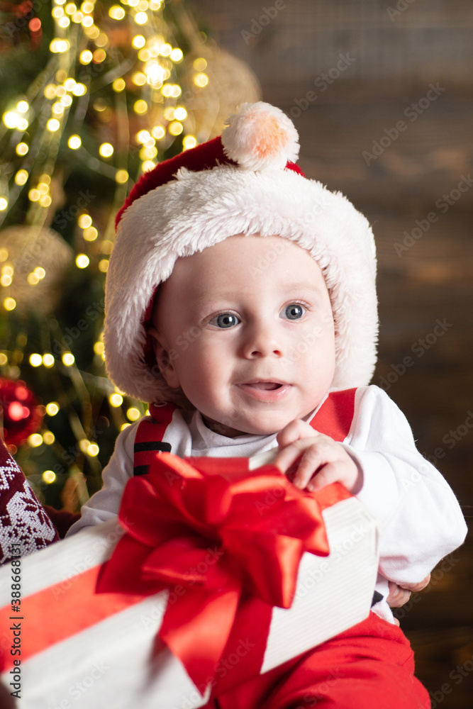 Wall mural portrait of funny baby in santa clothes and christmas hat. new year fun.