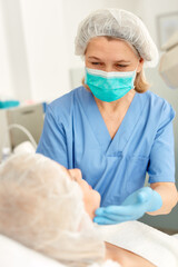 Fototapeta premium Professional cosmetician examining face skin of girl in clinic of esthetic cosmetology. High quality photo