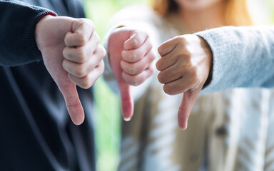 A group of people making thumb down hands sign in circle