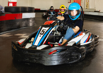 Man and women competing on racing cars at kart circuit