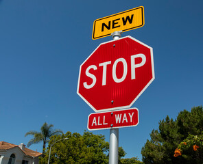 A recently installed stop sign with a small sign in yellow with the word New on top of the stop sign