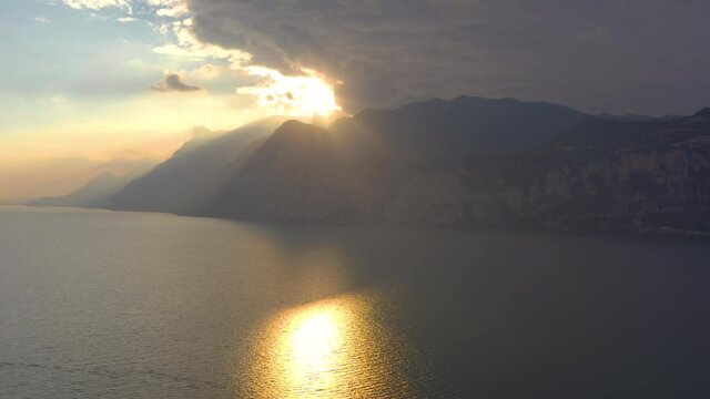 Aerial shot of the sunset sun breaking through the clouds and spilling amazing, warm, soft, golden light over the majestic mountains