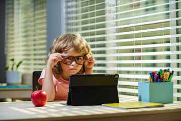 Back to school. First day at school. Cute little boy child using laptop computer, studying through...