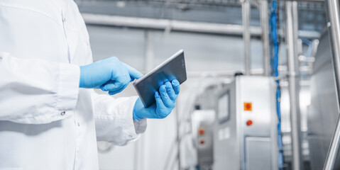 Man worker holding tablet computer checking production line dairy factory food industry. Copy space banner