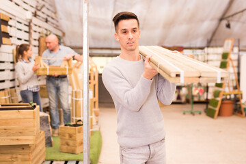 Young man buying wood panels at garden material warehouse..