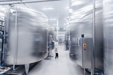 Operator female in uniform uses control panel manage process dairy plant food factory production line