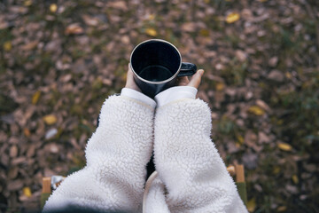 森でホーローカップを持ちイスに座り休憩する女性