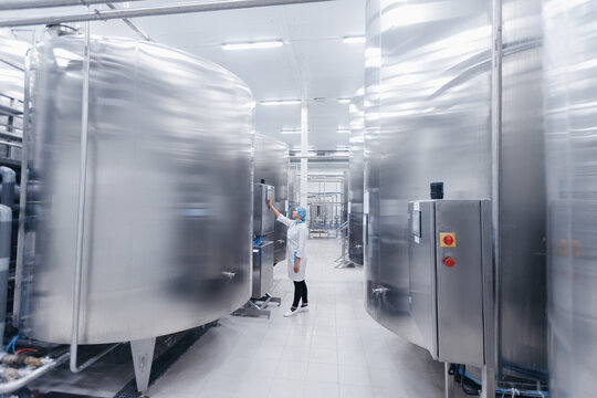 Operator female in uniform uses control panel manage process dairy plant food factory production line