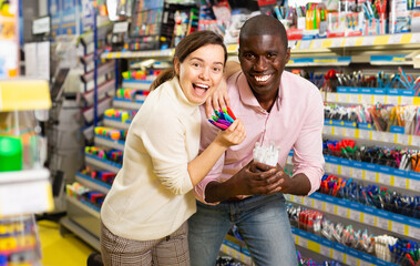 African american male and casual woman looking different pens in stationery store