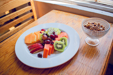 Plate with fruit slices and granola on a wooden table