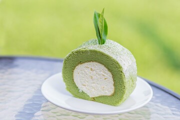 Green tea cake and roll with tea leaf  on white dish.
