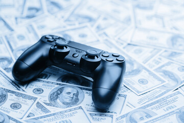 Concept of gaming addiction. Close up photo of gamepad on the money background.