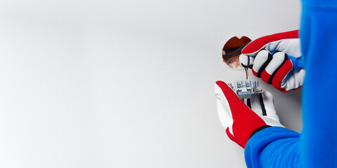 electrician installing light switch on painted wall with screwdriver. Man installing light switch after home renovation.