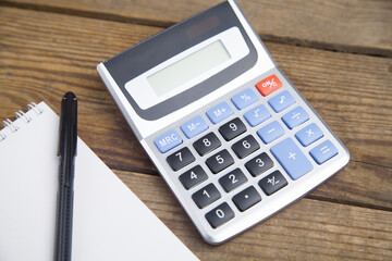 Notebook, pen and calculator isolated on wooden background.