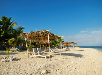 Sun chairs with thatched umbrella on a white sandy beach