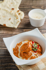 Butter chicken bowl and naan bread on wooden table. Curry - Meal, Indian food.