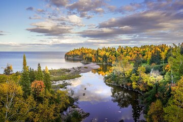 Beautiful reflections of clouds and Autumn colors on the Baptism River where it meets Lake Superior at Tettegouche State Park, Minnesota