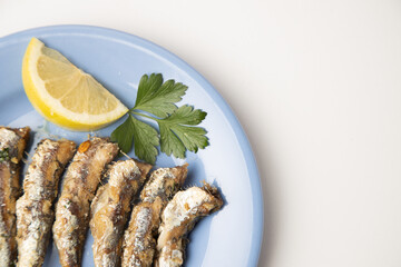 fried sardines, in blue plate with lemon wedge