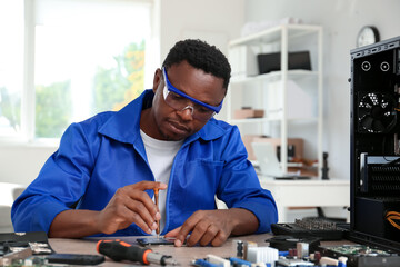 African-American technician repairing computer in service center