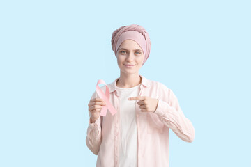 Optimistic woman after chemotherapy holding pink ribbon on color background. Breast cancer awareness
