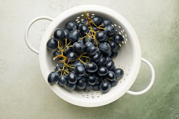 Colander with sweet ripe grapes on table