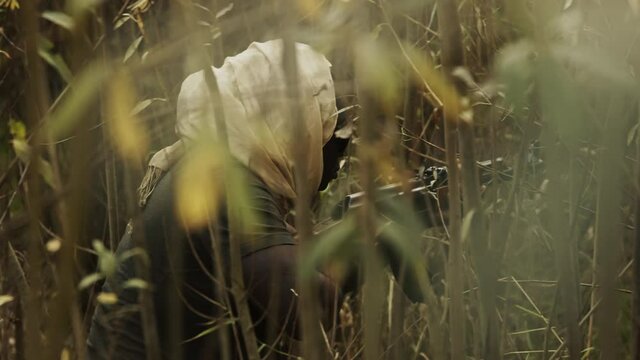 Concept of terrorism. Rebel soldier aiming at targets with an machine gun. Close up.