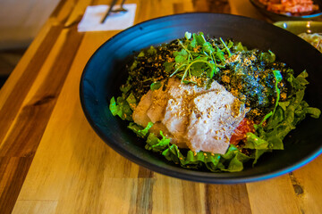 Korean mixed rice with meat, Bibimbap, with vegetables on a black bowl