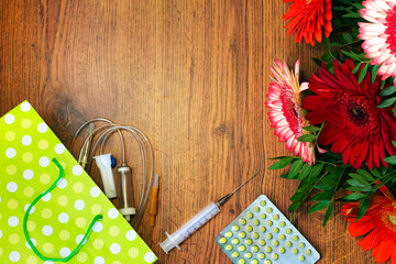 Doctor or nurse day greeting card with syringe, gerberas and dropper on wooden background.