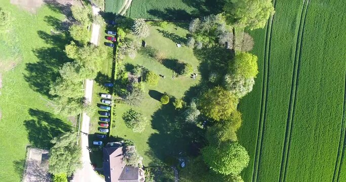 Top down shot flying above a farm and surrounding fields of green gras and brown earth