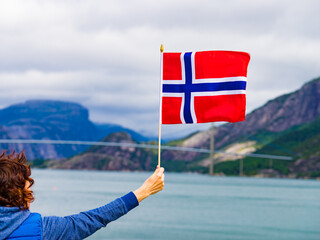 Tourist with norwegian flag on fjord