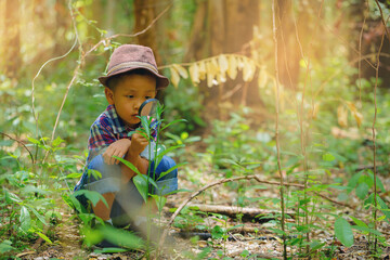 Happy little boy with magnifying glass explorer and learning the nature at home backyard	