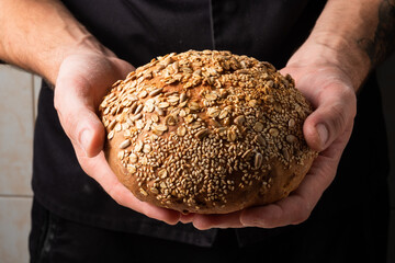 A loaf of fresh bread in the male hands of a baker. Yeast free healthy homemade bread. Spicy, fresh...