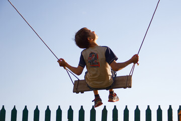child rides on a swing against a blue sky