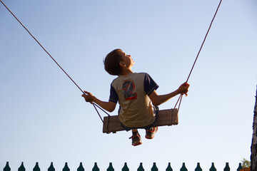child rides on a swing against a blue sky