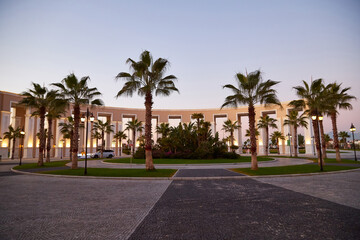 Palm trees and a colonnade with white columns in a small town square.