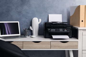 Modern printer and laptop on white table indoors