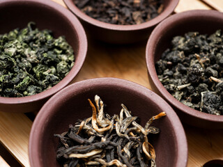 Assortment of Chinese tea in clay bowls on a wooden table