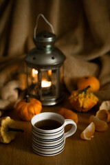 warm autumn still life with a cup of tea and small pumpkins, all souls day