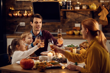 Happy family toasting during Thanksgiving meal in dining room.