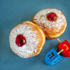 Fresh donuts and wooden dreidels for Hanukkah celebration.  Hebrew letters on color dreidels say : Great Miracle Happened Hear.
