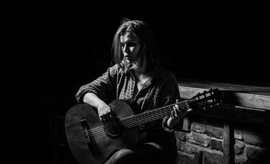 Woman playing guitar, holding an acoustic guitar in his hands. Girl guitarist plays. Girl play the...