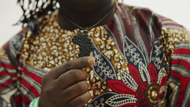 Close up shot of a hand holding a black necklace pendant in the shape of Africa.