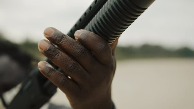 Afro-American man reloads pump action shotgun. Close up.