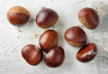 Obraz premium Eight chestnuts on white painted wooden background, top view.