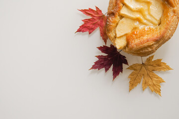 Apple danish with maple leaves on white back ground, top view