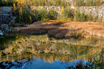 Beautiful reflection of autumn colored trees in water, landscape of abandoned and flooded s,all quarry, Czech Republic